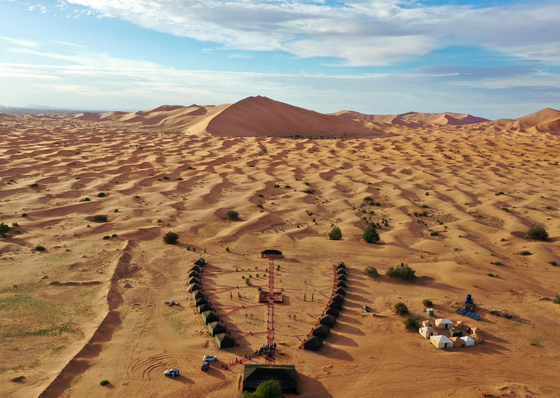 Vue aérienne des dunes de Merzouga avec un pilote en chèche noir contemplant l'immensité du Sahara